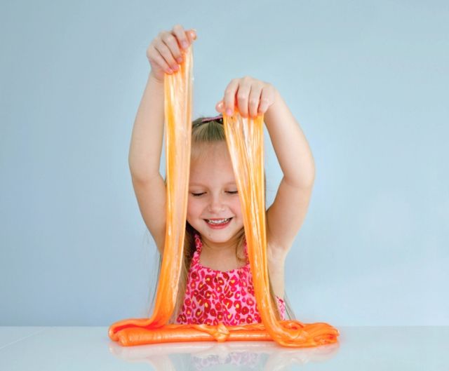 Девочка играет с оранжевым слаймом